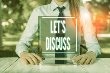 Text sign showing Let S Discuss. Business photo text asking someone to talk about something with demonstrating or showing Female business person sitting by table and holding mobile phone