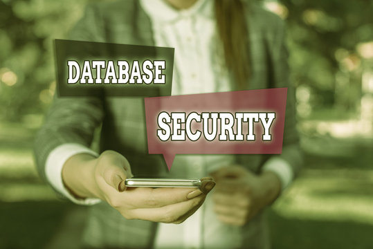 Conceptual hand writing showing Database Security. Concept meaning security controls to protect databases against compromises Woman in grey suites holds mobile phone
