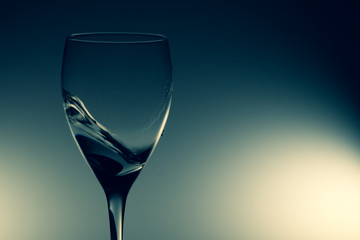 Water splash in glass on glowing background. splashing water in wine glass. transparent liquid