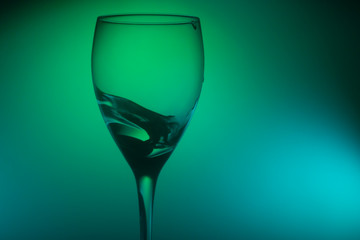 Water splash in glass on glowing background. splashing water in wine glass. transparent liquid