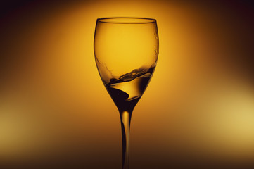 Water splash in glass on glowing background. splashing water in wine glass. transparent liquid