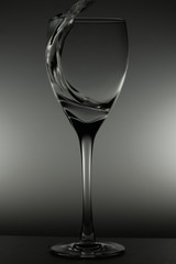 Water pouring into glass. water splash in glass on glowing background. transparent liquid splashing in wine glass