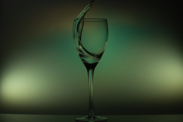 Water pouring into glass. water splash in glass on glowing background. transparent liquid splashing in wine glass