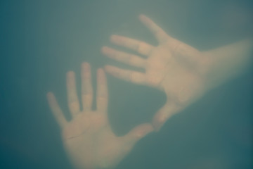 Hands behind the frosted glass. hands silhouette in the mist. loneliness concept. palm touches the glass window