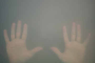 Hands behind the frosted glass. hands silhouette in the mist. loneliness concept. palm touches the glass window