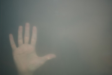 Hand behind the frosted glass. hand silhouette in the mist. loneliness concept. palm touches the glass window