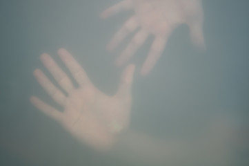 Hands behind the frosted glass. hands silhouette in the mist. loneliness concept. palm touches the glass window