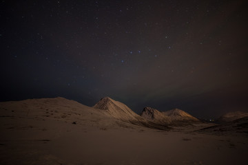 Dramatic night with many clouds and stars on the sky over the mountains in the North of Europe - Tromso, Norway.long shutter speed.