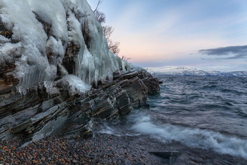 Icicles hanging from the rocks on the shore Tornetrask, Sweden. Polar night. long shutter speed