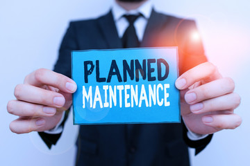 Writing note showing Planned Maintenance. Business concept for reventive maintenance carried out base on a fixed plan Male human wear formal work suit with office look hold book