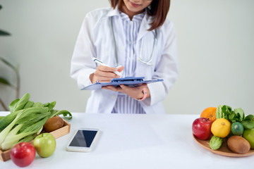 Portrait of young smiling female nutritionist in the consultation room. Dietitian working on diet plan.