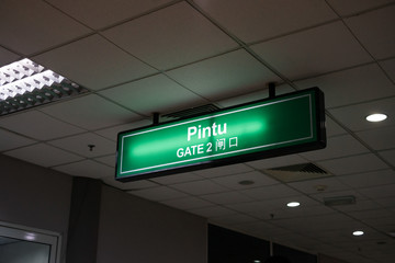 Airport gate signage written in chinese, english and malay.