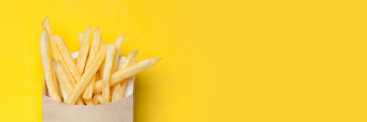Web-banner with French fries in a cardboard box on the yellow background. Copy space.