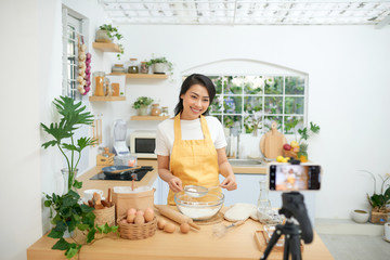 Pretty young asian female food blogger working on a new video and explaining how to cook a dish