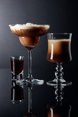 Coffee cocktails and liquor on black reflective background.