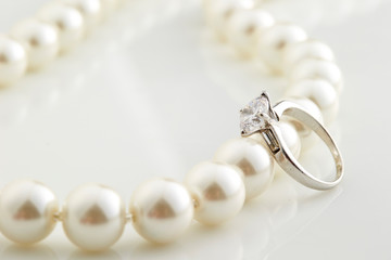 Pearl necklace and ring on white background 