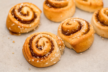 Freshly baked cinnamon buns rolls on a tray lined with baking parchment paper