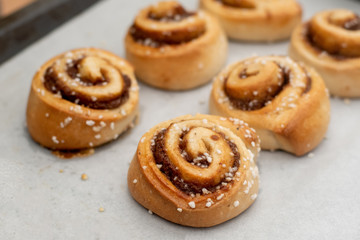 Freshly baked cinnamon buns rolls on a tray lined with baking parchment paper