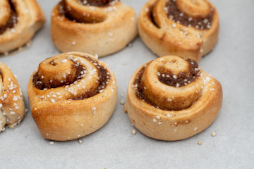 Freshly baked cinnamon buns rolls on a tray lined with baking parchment paper