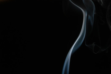 Abstract smoke background with copy space on black background. Blue-white smoke rising from the incense stick
