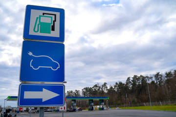 Road sign, pointed out to power station, with usual kinds of fuel and electric vehicle charging station (EV), on blue background.