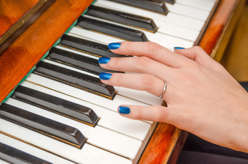 Fototapeta premium hand of a young woman with blue nail Polish plays the piano close up