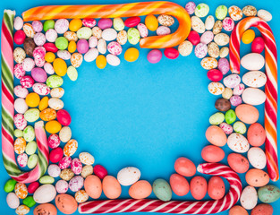 Colorful frame of multicolored candies on a blue background. Circle copy space, top view.