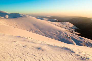Fototapeta na wymiar Panoramic sunset view of winter mountain hills covered with snow