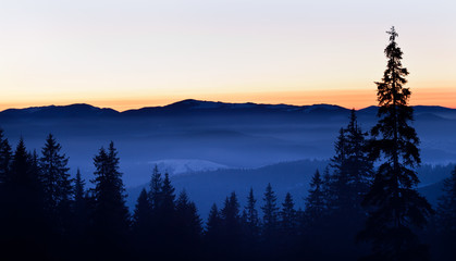 Panoramic view of winter hills and valley covered with snow and white smoke