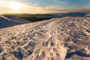 Sunset over mountains covered with snow in winter clear day © YouraPechkin