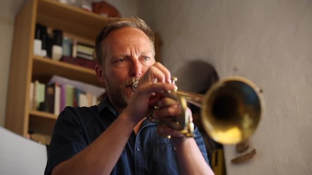 Hombre de mediana edad de pelo rubio tocando la trompeta