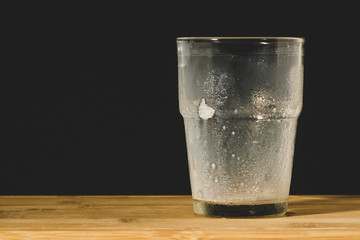 Glass of milk on a wooden surface and black background