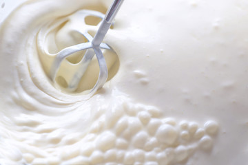 Whipping cream with a mixer. Bubbles on cream
