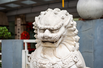Statue of a Chinese dragon. Head of a lion from white marble, grin fangs