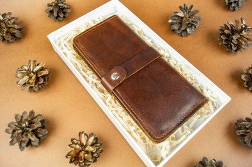 Fototapeta na wymiar wallet made of genuine leather on the table in the process of packing a gift on a brown background
