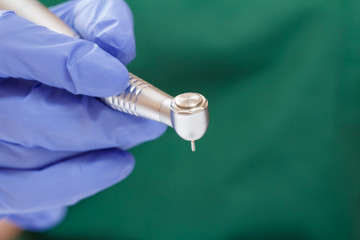Dentist's hand in glove with dental handpiece.