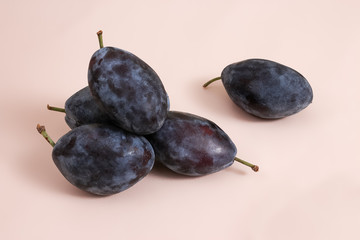 Ripe sweet plum fruits on the pink background
