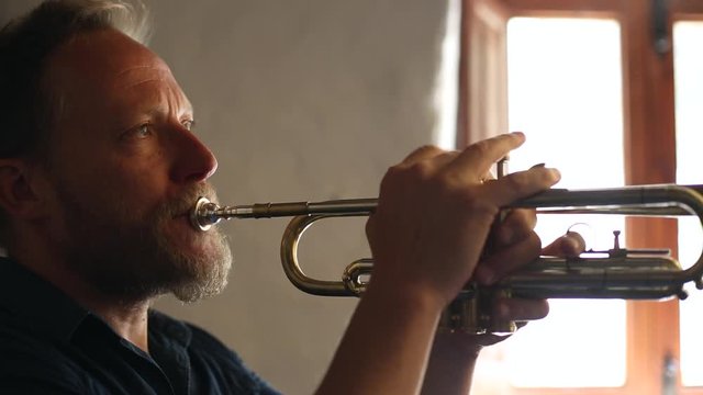 Hombre de mediana edad de pelo rubio tocando la trompeta