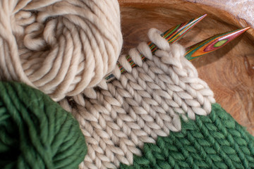 beige and green knitting on wooden needles 