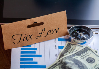 Tax Law Words on tag with dollar note,smartphone,compass and graph on wood backgroud,Finance Concept
