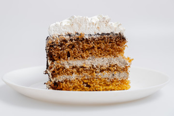 A large piece of biscuit cake on a white plate. Eating sugary food rich on carbs concept