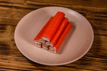 Ceramic plate with pile of crab sticks on a wooden table