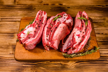 Raw pork ribs with spices and rosemary on a cutting board