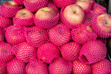 A apple pile with pink foam nets for sale
