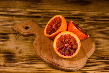 Cutting board with halved sicilian oranges on a wooden table
