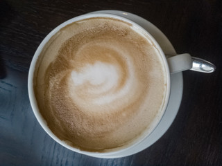 Top down close up shot of latte art cup on dark surface. Concept of morning coffee.