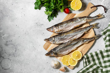 Smoked or dried fish smelt on a wooden Board on a gray kitchen table	
