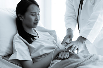 Young male doctor holding Asian female patient hand at hospital bed and hand with fluid replacement therapy, saline intravenous for set,Healthcare and medically concept