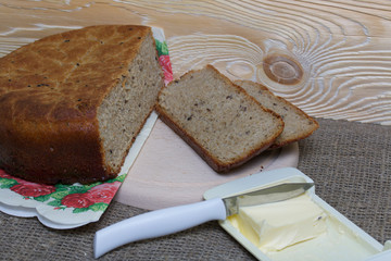 Freshly baked bread. Slices of bread are cut and lie next to them on a cutting board. It’s a carnival with butter and a knife. The surface is covered with linen.