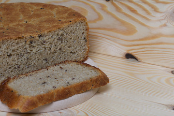 Freshly baked bread. A loaf of bread is cut and lies on a cutting board. Background from pine...